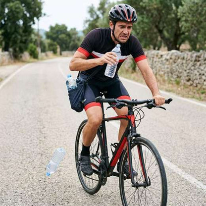 Ciclista sin soporte sosteniendo la botella con la mano